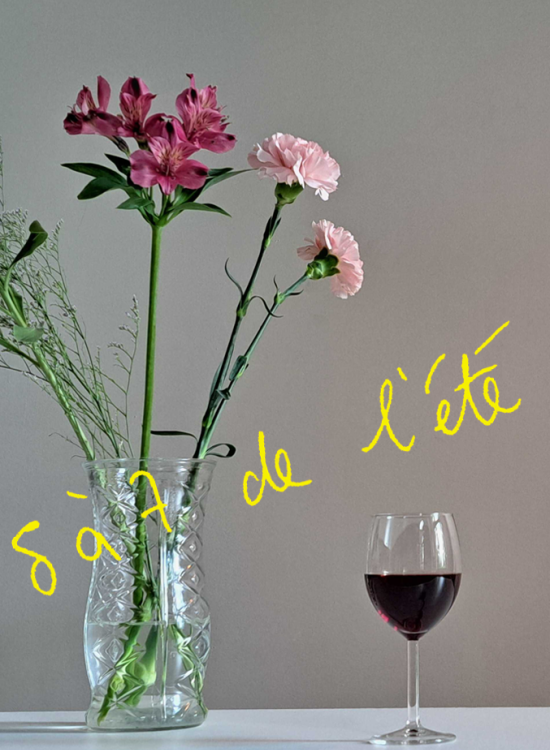 L'image montre un vase en verre contenant des fleurs diverses, principalement blanches et roses, posé sur une table blanche. À côté du vase, il y a un verre de vin rouge. On peut lire l'inscription en jaune "Les 5 à 7 de l'été" sur l’image. L'ensemble de la scène donne une impression de simplicité et d'élégance, évoquant une ambiance estivale et détendue.